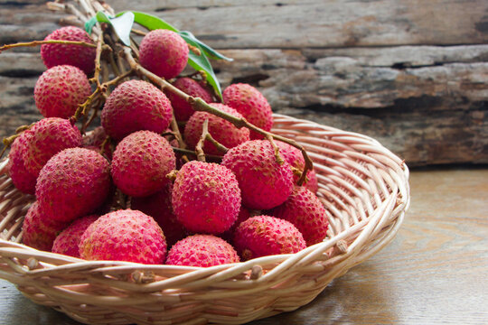 lychee fruits in wicker basket on wooden table.