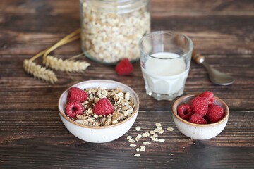 Healthy breakfast with muesli cereal mix, milk and fresh raspberries. Selective focus