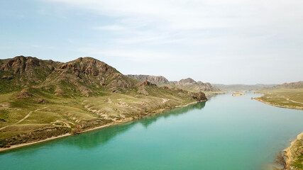 Broad river ILI. People run and play sports along the river. Top view from a drone. The water reflected the green hills, the sky and the grass. Running on the road in nature. Kazakhstan.
