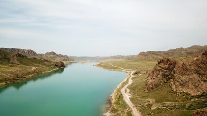Broad river ILI. People run and play sports along the river. Top view from a drone. The water reflected the green hills, the sky and the grass. Running on the road in nature. Kazakhstan.