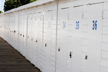 Set of changing cabins on the beach, all white with numbered doors