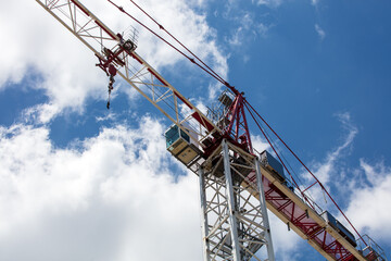 Construction crane control center against a blue sky with puffy white clouds