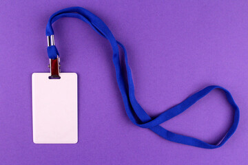 Vertical white badge with a blue lace around the neck. Badge on a purple background