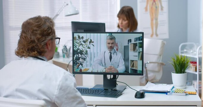 Senior specialist communicates with his colleagues via video, giving advice on treatment of patients. Concept of using technologies for remote medical care.