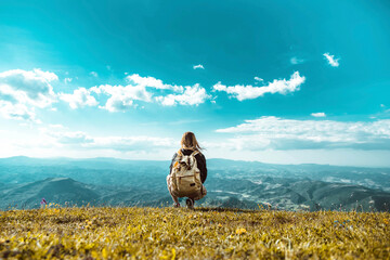 Hiker with backpack relaxing on top of a mountain and enjoying valley view  - Traveler woman...