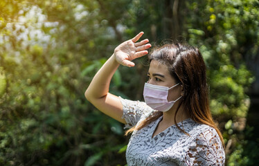 Woman wearing a pink mask and hands blocking the sun.