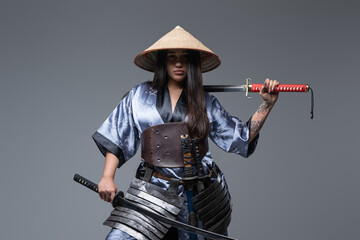 Young female warrior with samurai swords and bamboo hat