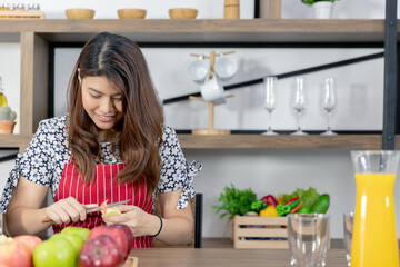Portrait of young Asian healthy beautiful woman with casual clothes is  smiling and slicing fresh fruit to diet at home in kitchen romm in holiday.