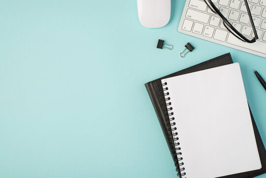 Top view photo of planners binders pen glasses white mouse and keyboard on isolated pastel blue background with copyspace