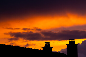 Dark storm clouds during sunset and silhouette of chimney with dramatic sky and vibrant colors