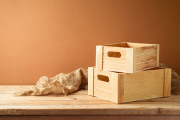 Empty wooden box on rustic table with sackcloth over  wall  background.  Harvest mock up for design...