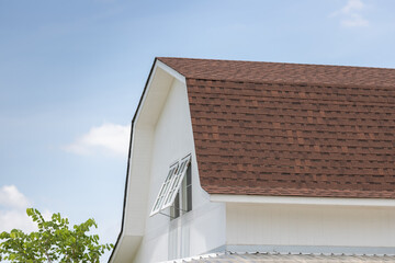 brown roof shingle of house against blue sky.