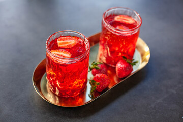 Red drink with ice and strawberry with leaves