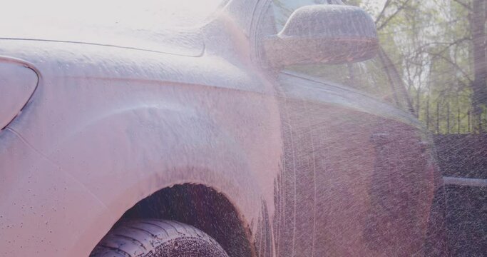 Covering car by foam, spreading of soap on car exterior in car wash, auto service. Carwash, car detailing concept