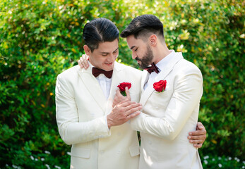 A couple of Caucasian LGBTQ are wearing white suit, hugging together, wedding celebrate and standing outdoor.Diversity married concept.