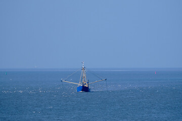 Ameland, Netherlands-April,19,2021: Fishing boat, nets and seagulls on the Wadden Sea. Fisherman...