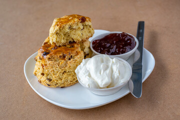 Scones with jam and cream on white plate