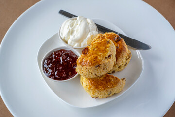 Scones with jam and cream on white plate