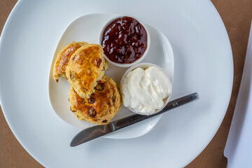 Scones with jam and cream on white plate