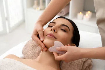 Papier Peint photo Lavable Salon de massage Young woman receiving facial massage with gua sha tool in beauty salon