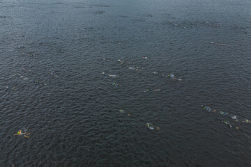 Triathlon swimming contest in lake swimmers competition aerial drone photo.  Group of swimmers during a competition in the sea