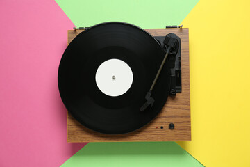 Turntable with vinyl record on color background, top view