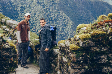 Obraz premium Two backpackers male friends smiling at camera on Phuyupatamarca ruins. Inca trail to Machu Picchu archaeological site from the Inca's ancient civilization in Peru. South America