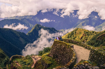 High angle distant view of three backpacker male friends contemplating the huge valley in front on them on Phuyupatamarca ruins. Inca trail to Machu Picchu in Peru. South America © Damian Basante