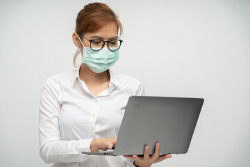 Asian female office worker wearing a mask using a laptop and talk on the mobile phone to contact the job financial transactions