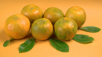Fresh orange citrus fruit with leaves isolated on yellow background. Juicy and sweet and renowned...