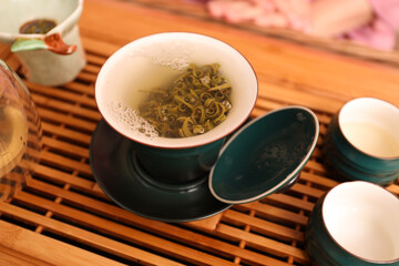 Cup with freshly brewed tea during traditional ceremony on wooden table
