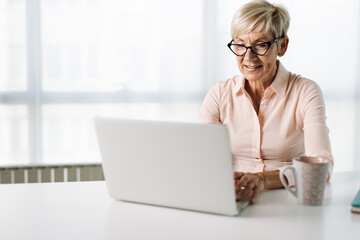 Smiling mature businesswoman reading an e-mail on her computer in the office