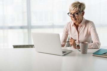 Mature businesswoman reading an e-mail on her computer in the office
