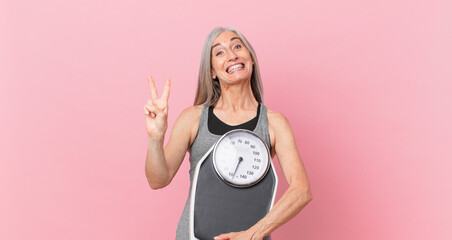 middle age white hair woman holding a weight scale. fitness and diet concept
