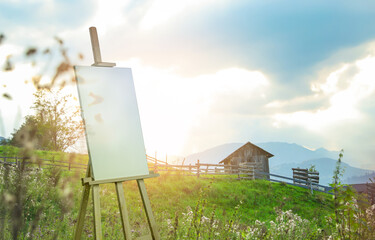 Wooden easel with blank canvas and picturesque view of village on mountain slopes