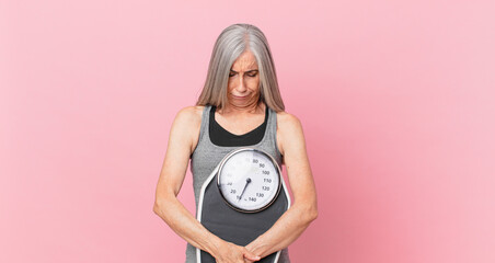 middle age white hair woman holding a weight scale. fitness and diet concept