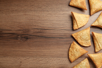 Fresh delicious crispy samosas on wooden table, flat lay. Space for text