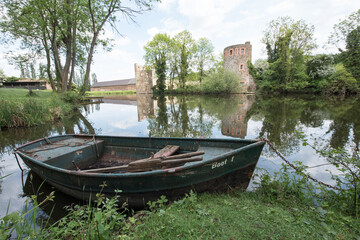mittelalterliche Wasserburg spiegelt sich im Wasser mit Boot im Vordergrund