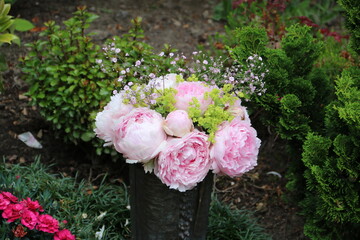Vase mit Pfingstrosen schmückt ein Grab auf dem Friedhof 