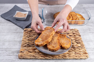 Woman with plate of fried bread with milk, egg, sugar and cinnamon (Torrijas). Typical Spanish Easter sweet. Traditional home cooking concept. Horizontal photography and selective focus