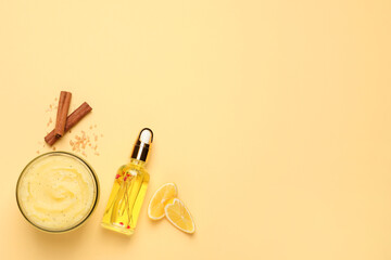 Body scrub in glass jar, oil, lemon and cinnamon on yellow background, flat lay. Space for text