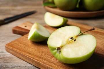 Cut fresh green apple on wooden table, closeup