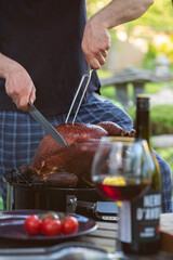 A man cuts up a whole turkey cooked on the grill in the garden