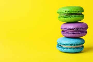 Delicious colorful macarons on yellow background, closeup, Space for text