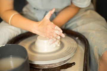 female hands make dishes from clay on a potter's wheel