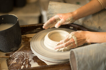 female hands make dishes from clay on a potter's wheel