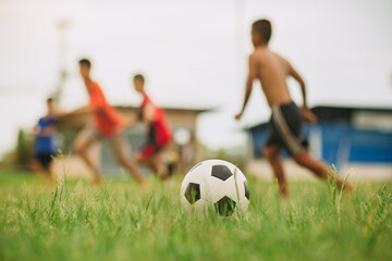 Fototapeta premium Action sport outdoors of kids having fun playing soccer football for exercise at the green grass field.