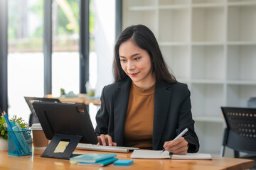 Image of Asian business women working in the office using laptop keyboard and taking notes at the office.