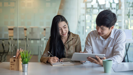 Obraz premium Team businessman and businesswoman Asian work together brainstorm discuss work by taking notes and tablet ready at the office.