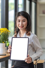 Asian businesswoman sitting holding tablet blank white screen. Looking at the camera.